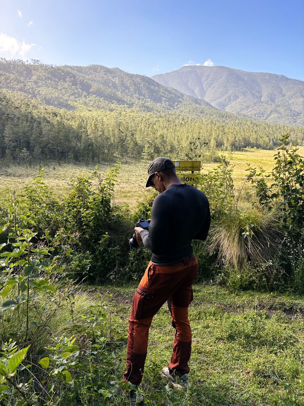 Ricardo checking his camera beside a mountain valley