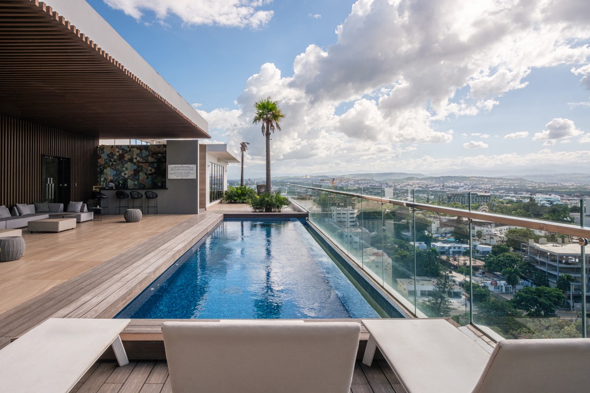 A rooftop pool extends toward the skyline beneath a timber canopy.