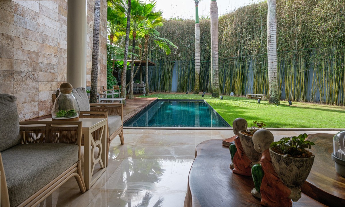 A shaded sitting area opens onto a narrow pool and green courtyard.