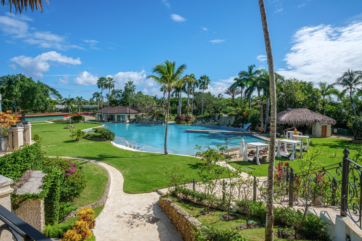 Curving paths and clipped lawns surround a palm-lined swimming pool.