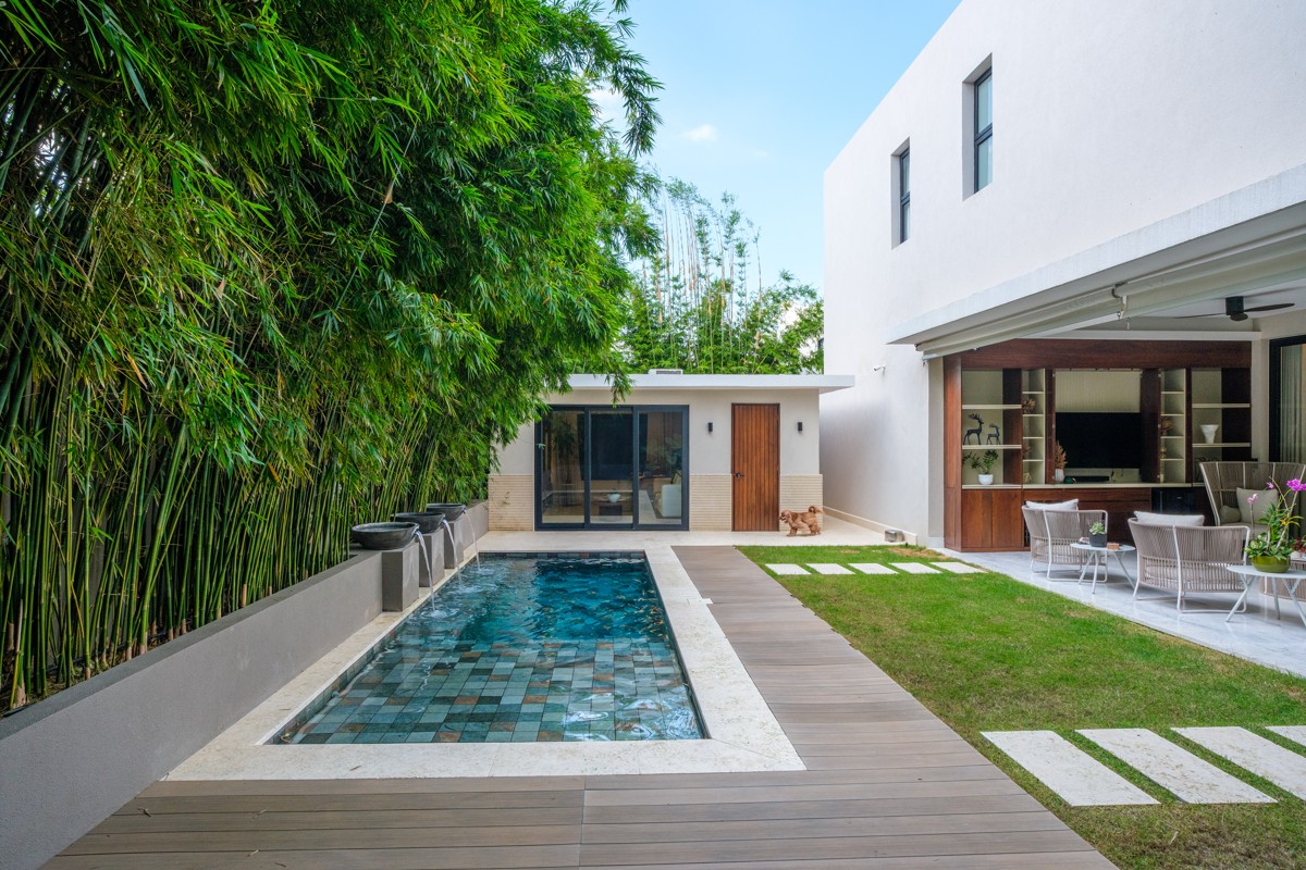 White walls, bamboo, and a strip of lawn enclose a private pool.
