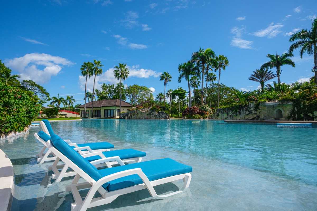 Blue loungers face still water beneath a bright tropical sky.