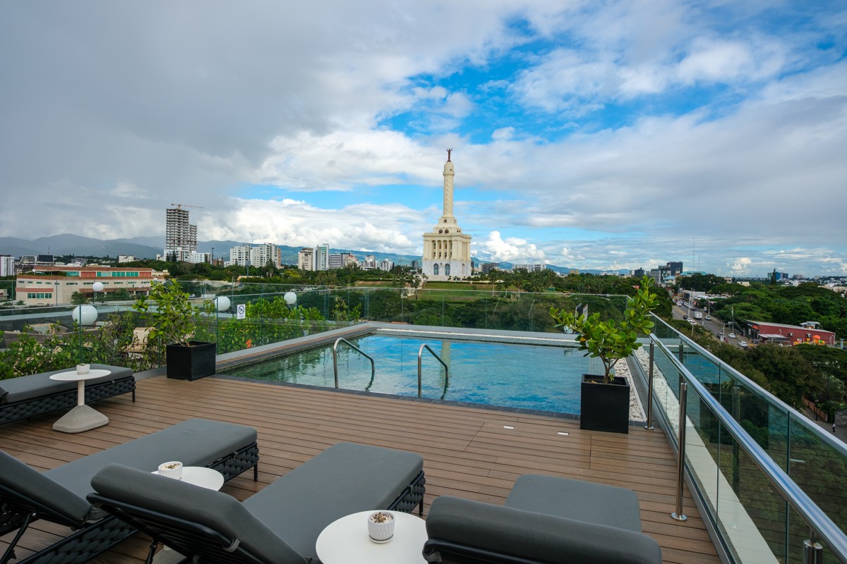 A rooftop pool overlooks a tower rising above the surrounding city.