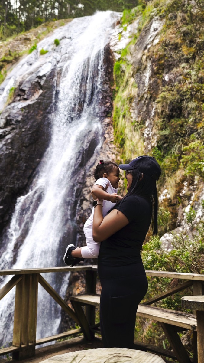A visitor stands at a railing in front of falling water.