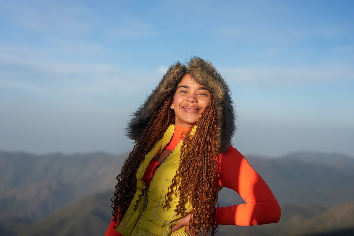 Warm light catches a smiling hiker and her loose curls.