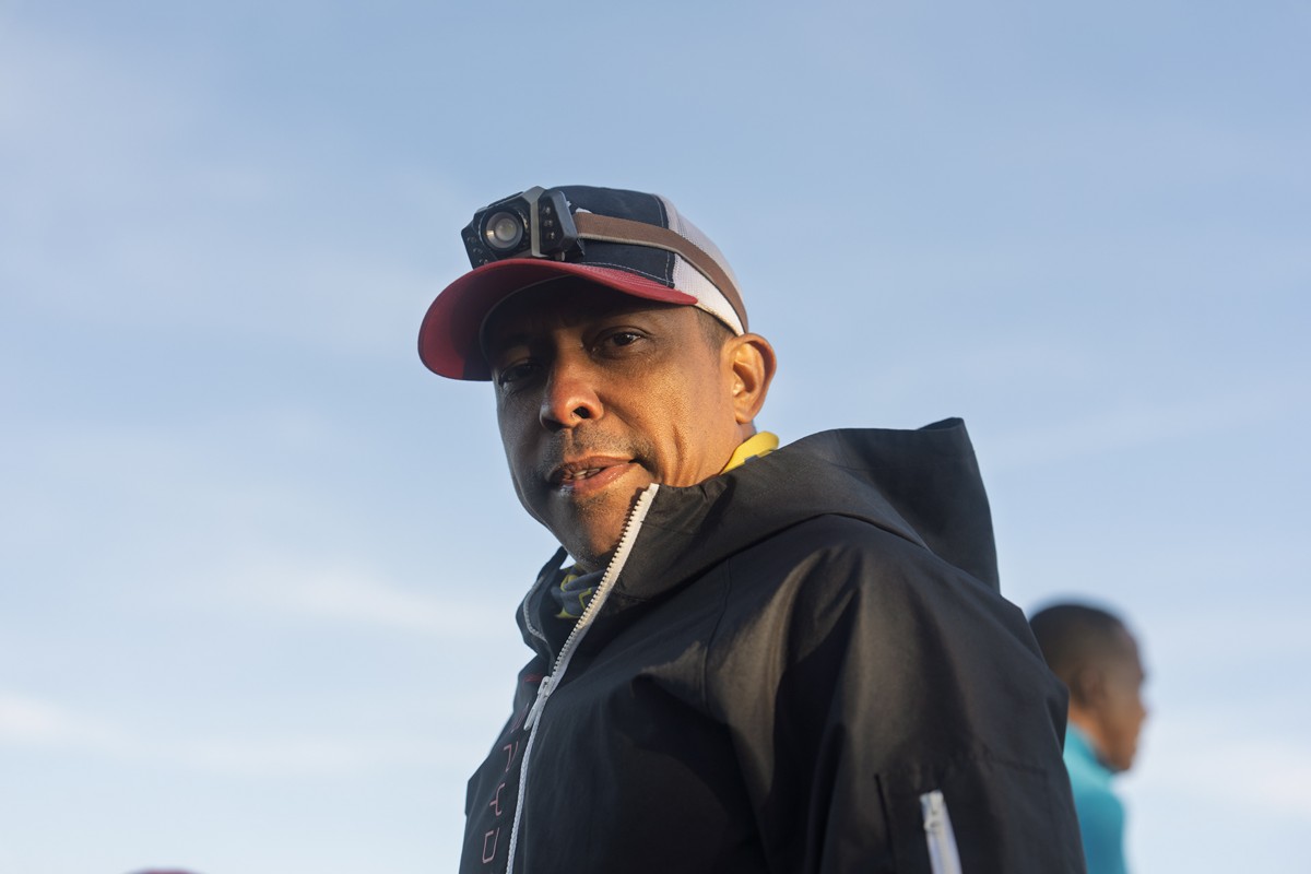 A hiker wears a small camera on the brim of his cap.