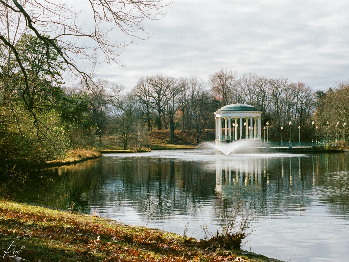 A white lakeside pavilion reflects in still water.