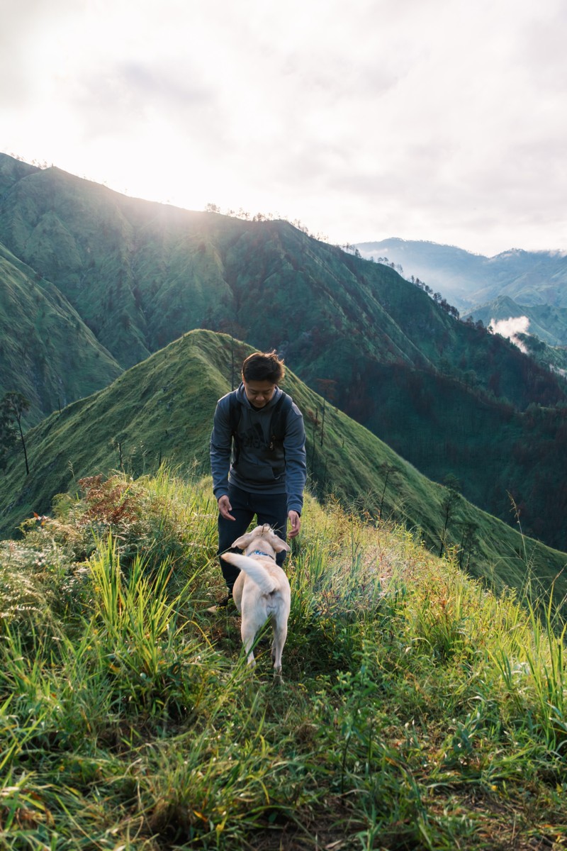 A hiker stands on a narrow ridge above steep valleys.