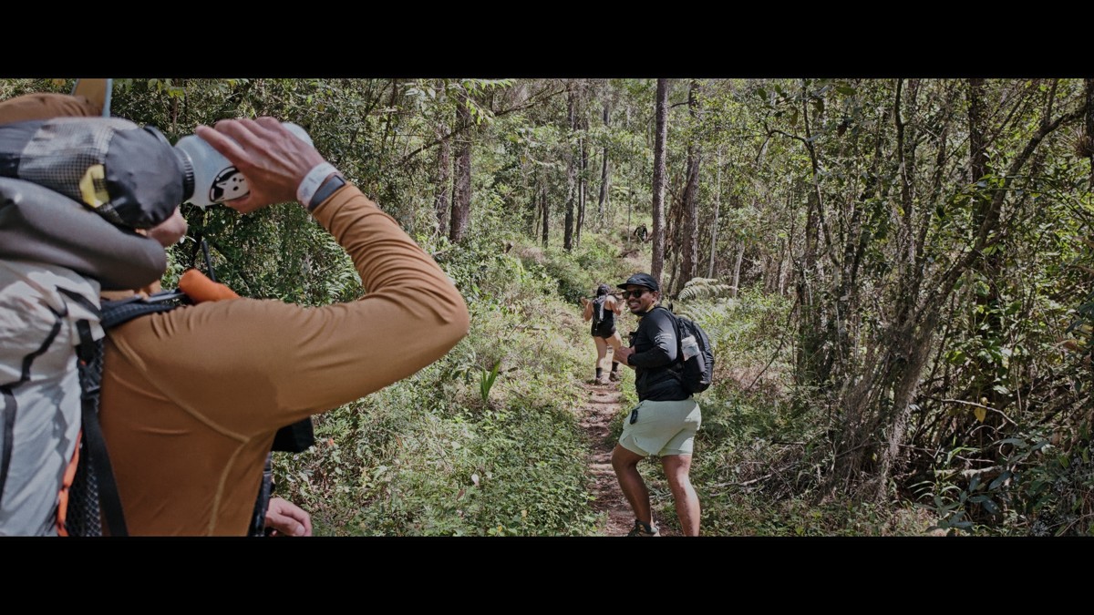 A backpacker raises a bottle during a woodland pause.