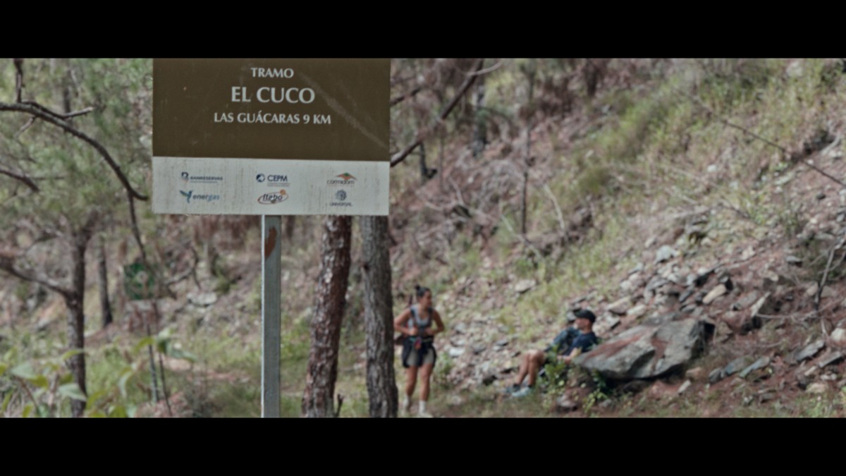 Hikers sit beneath a sign beside the rising path.