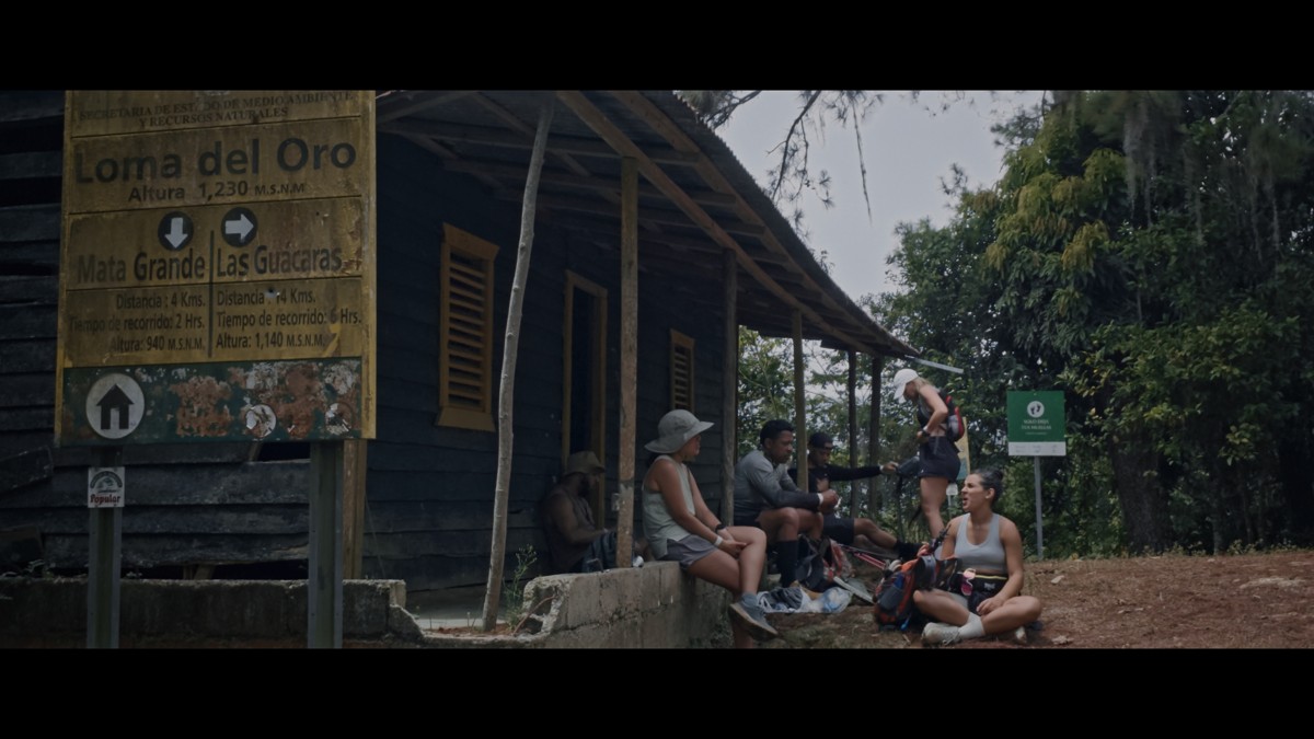 A group rests on the porch of a wooden trail building.