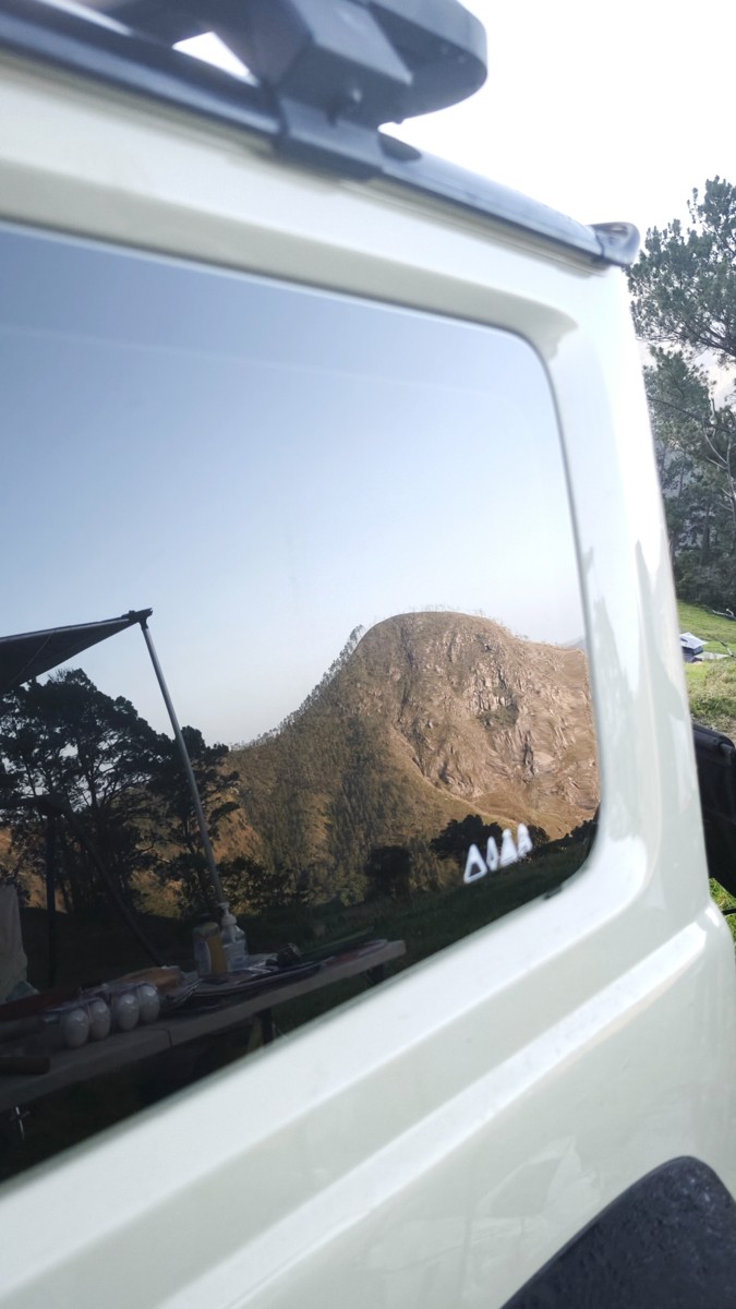 Mountains appear in the side window of a white vehicle.