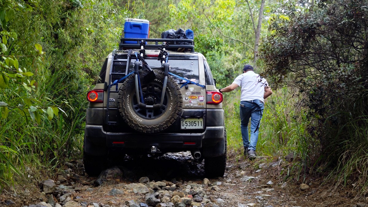 A person moves beside a loaded vehicle on a narrow stone track.