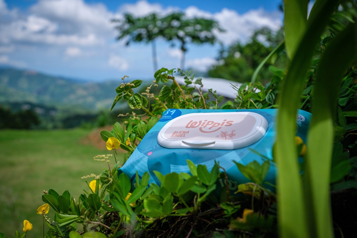 Product packaging sits in flowering foliage against an open landscape.