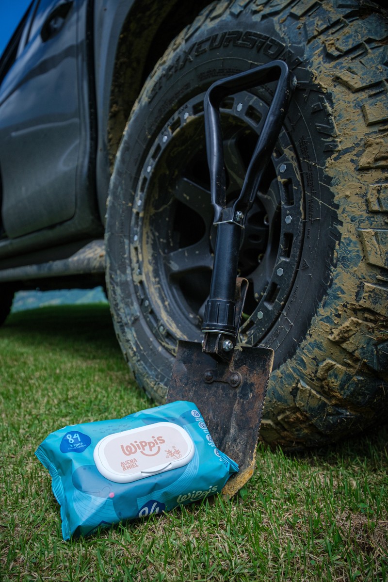 Blue packaging rests on the grass beside a rugged tire.