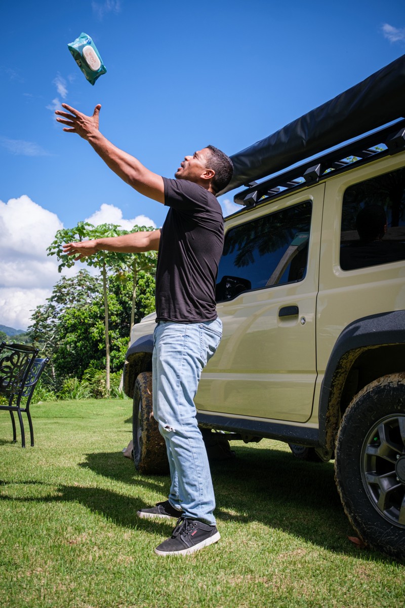 A person tosses the pack beside a parked off-road vehicle.