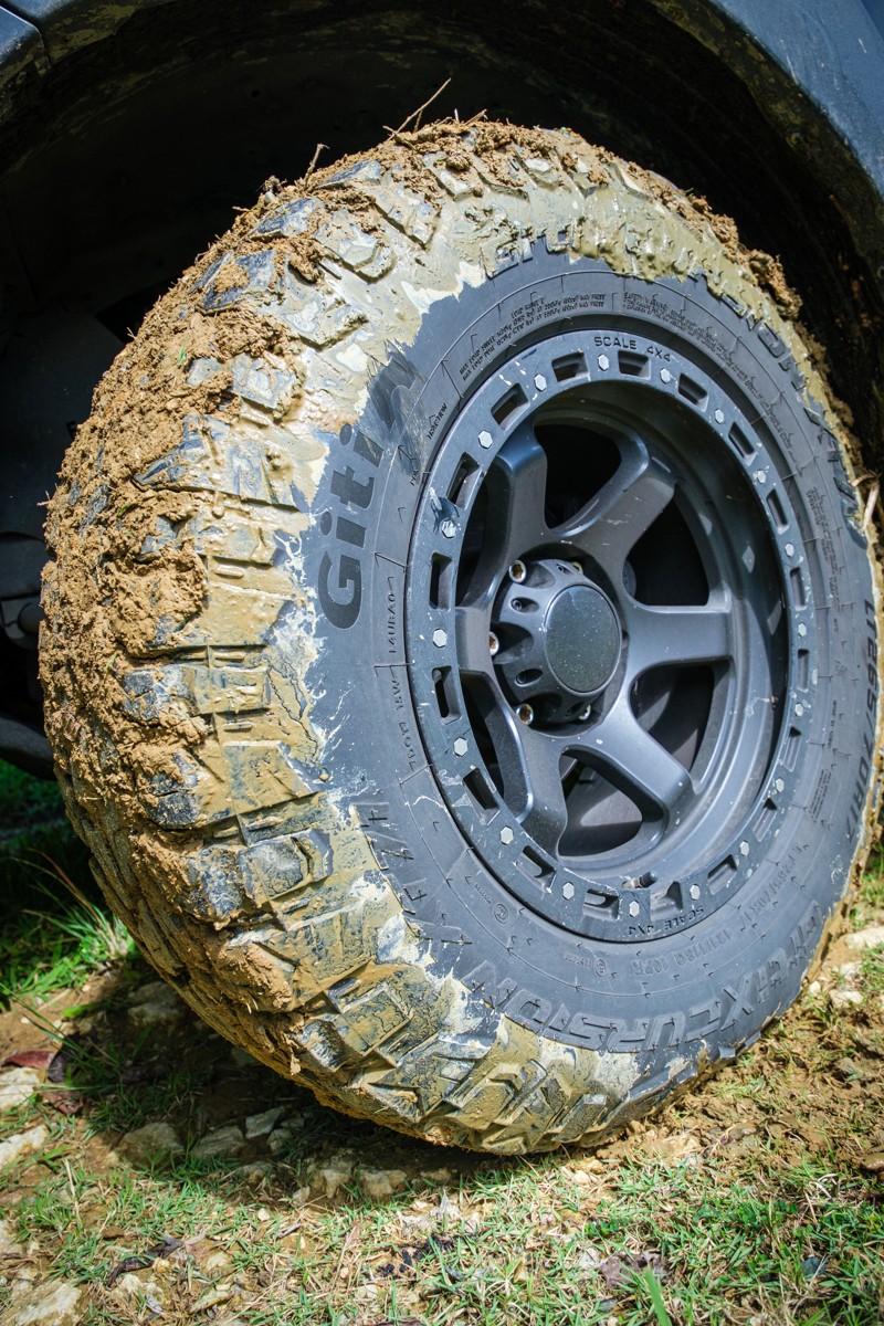 Mud fills the tread around a dark alloy wheel.